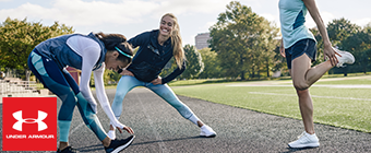 Three women stretching on a track wearing Under Armour